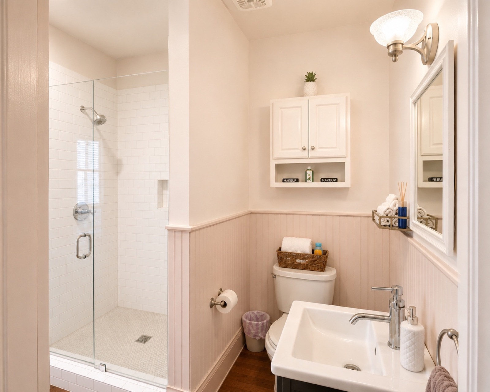 Renovated bath - glass shower, beadboard wainscot, brass sconce