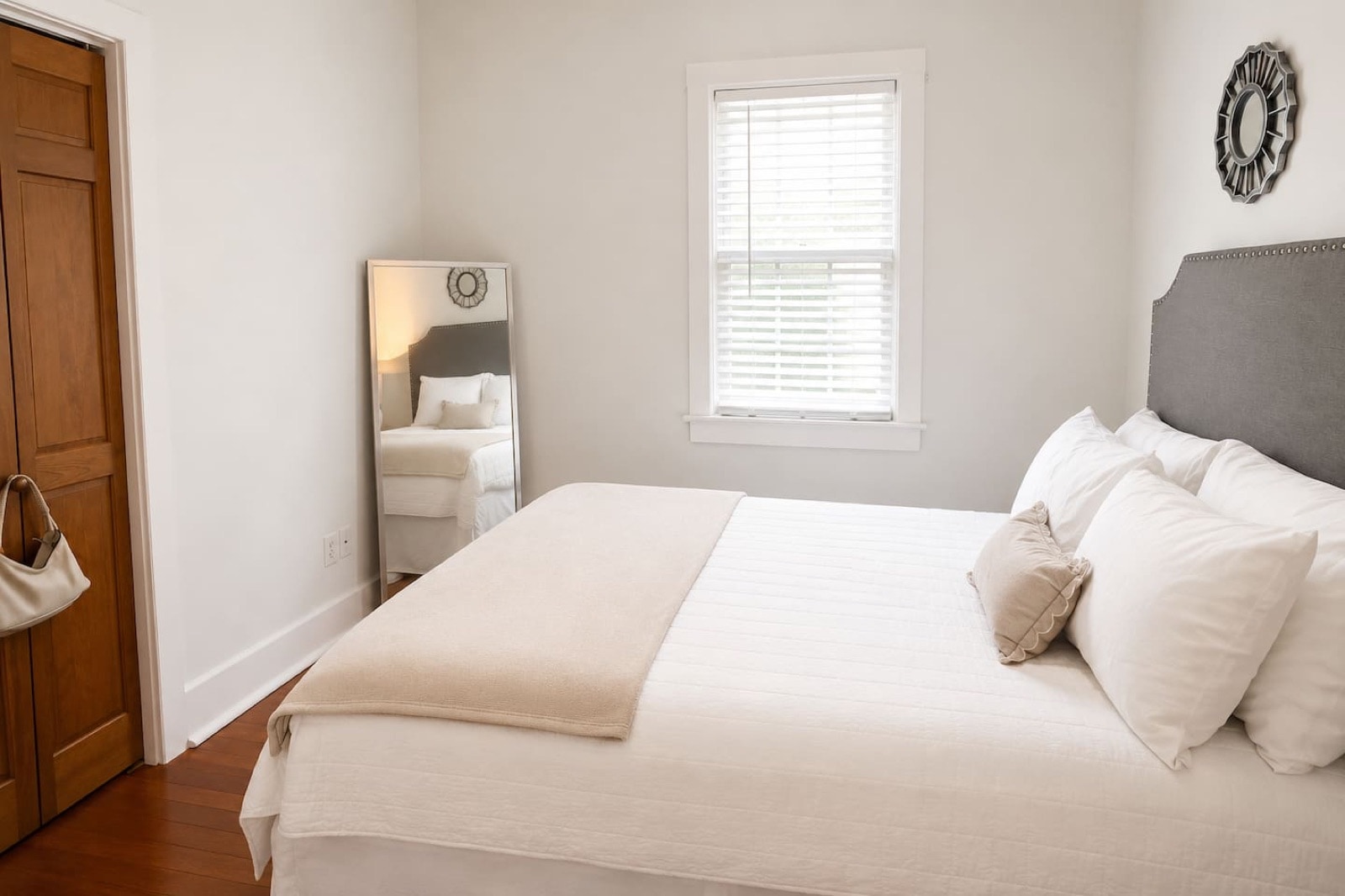 Queen bedroom - full room view with leaning mirror, clothing rack, and window light